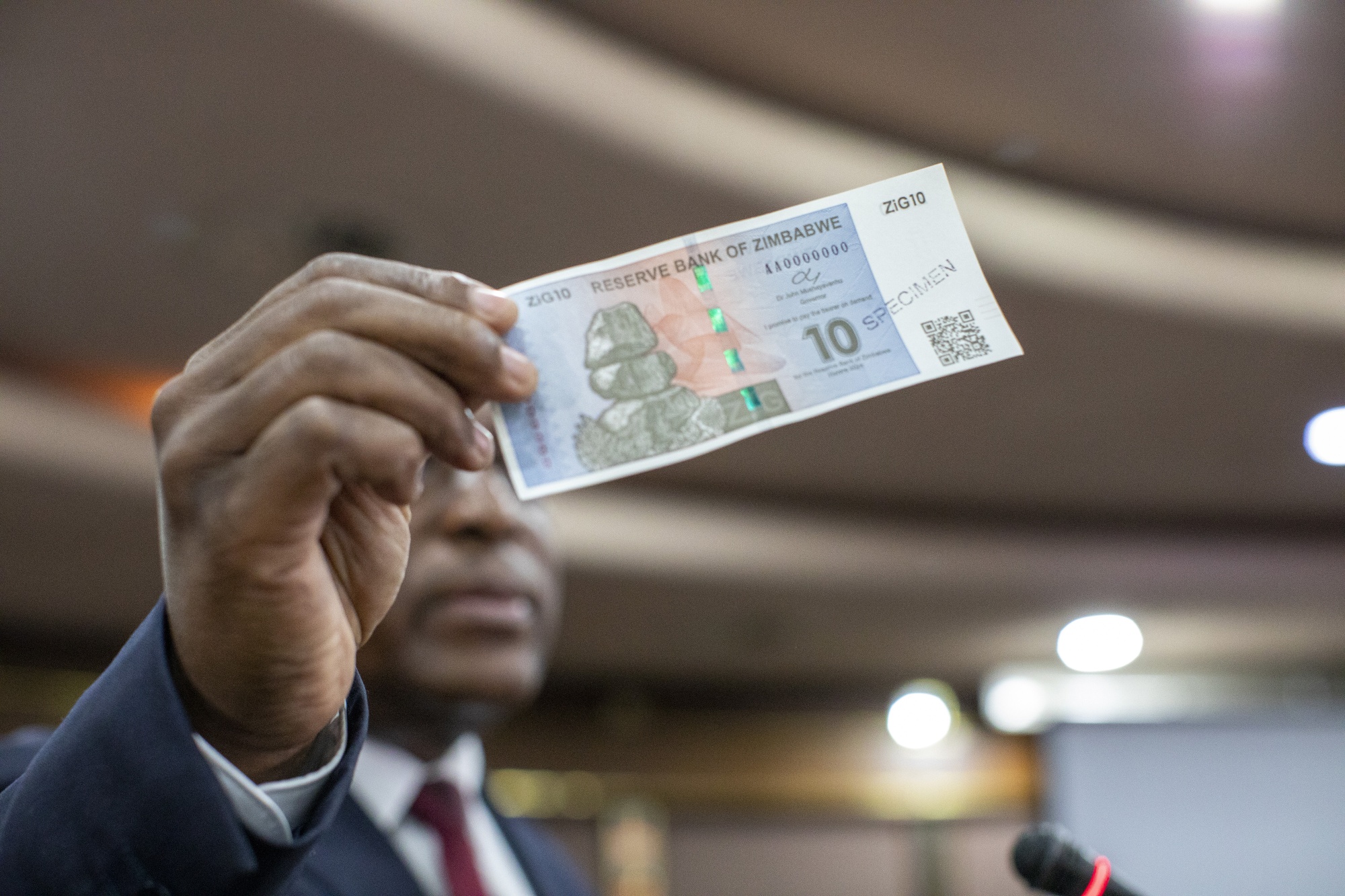 John Mushayavanhu holds up a specimen of the new gold backed currency ZiG banknote , in Harare.