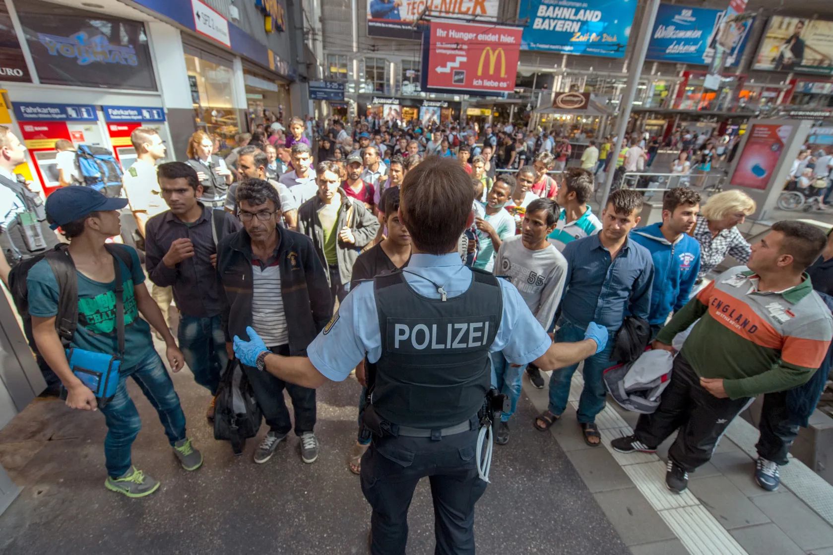 A policeman shows a refugee group the way to the registration office at the central train station in Munich, Germany, 31 August 2015. Around 50 to 60 refugees arrived by train from Hungary just before. Photo by: Matthias Balk/picture-alliance/dpa/AP Images
