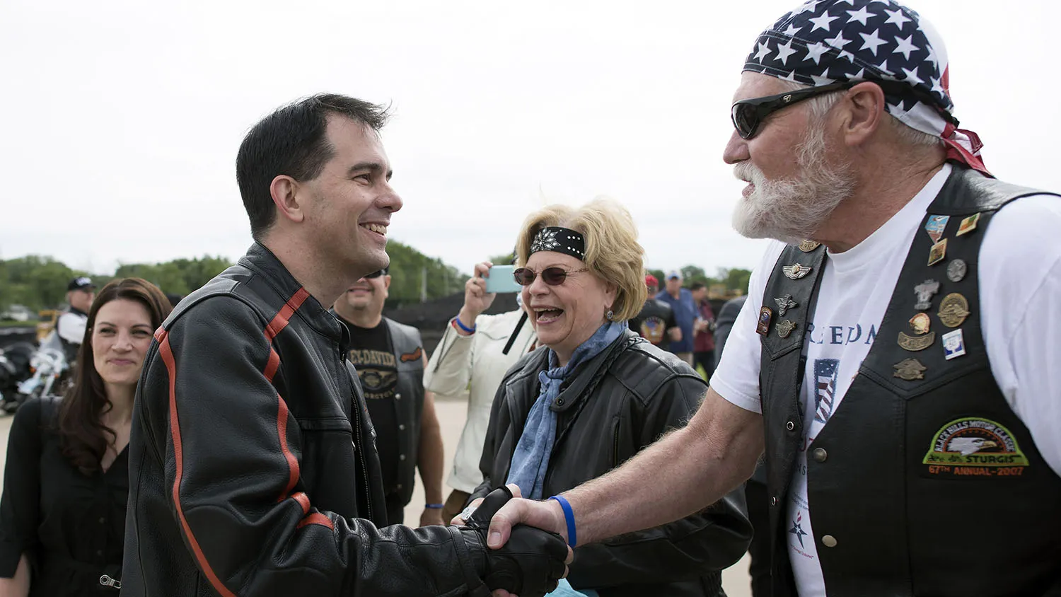 Scott Walker, governor of Wisconsin, greets an attendee as he arrives at Big Barn Harley Davidson in Des Moines, Iowa, U.S., on Saturday, June 6, 2015. Iowa Senator Joni Ernst is hosting the inaugural Roast and Ride event which featured a 38-mile ride from a Des Moines Harley Davidson dealership to the Central Iowa Expo where seven current and potential Republican presidential candidates are expected to speak.
