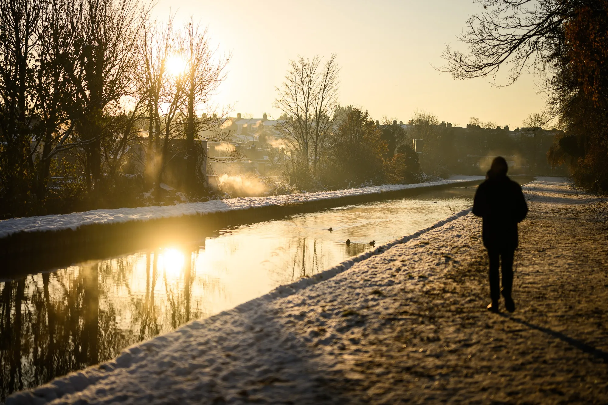 A man walks on a snow-covered path by a river in London, UK, on Dec. 16.&nbsp;London is expected to reach 2.8C below average on Monday.