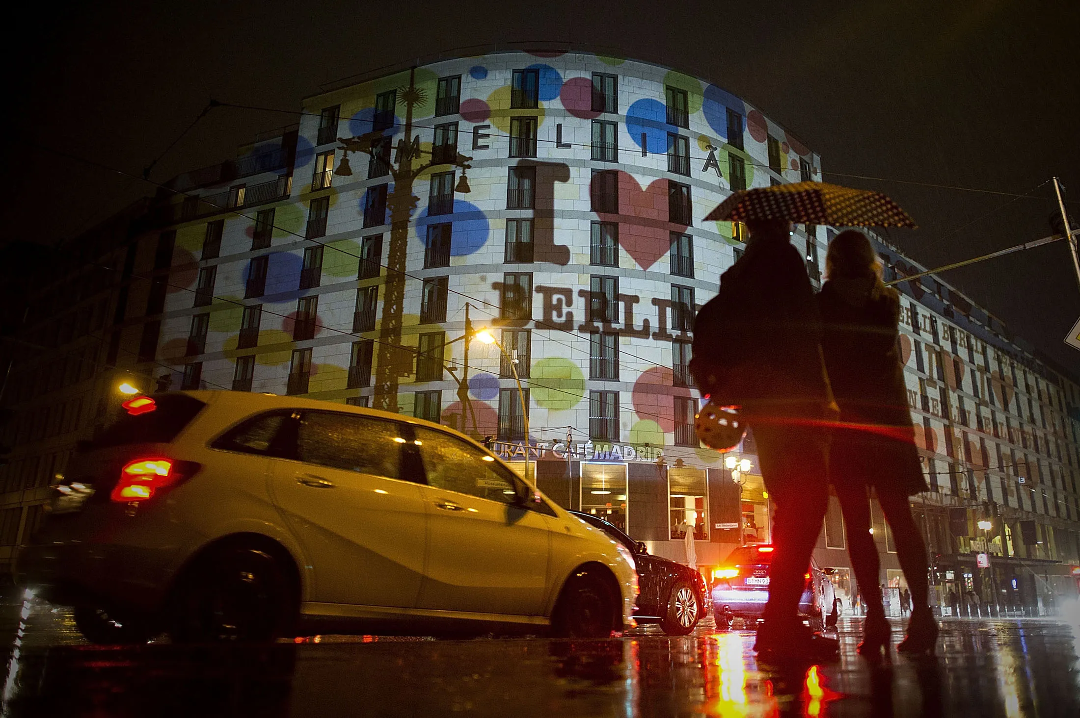 BERLIN, GERMANY - SEPTEMBER 10: People watch buildings along the river Spree in downtown Berlin, which are illuminated to celebrate the 20th jubilee of eBay on September 10, 2015 in Berlin, Germany. Swiss born light artist Gerry Hofstetter (not pictured) illuminated several buildings along the river Spree from the Berlin main train station to the East Side Gallery during the evening.

