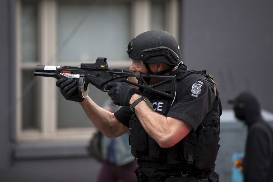 A police officer prepares to fire rubber bullets at demonstrators during an anti-capitalist protest in Seattle, Washington, on May 1, 2015.