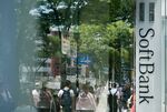 Pedestrians are reflected in the window of a SoftBank Group Corp. store in Tokyo.