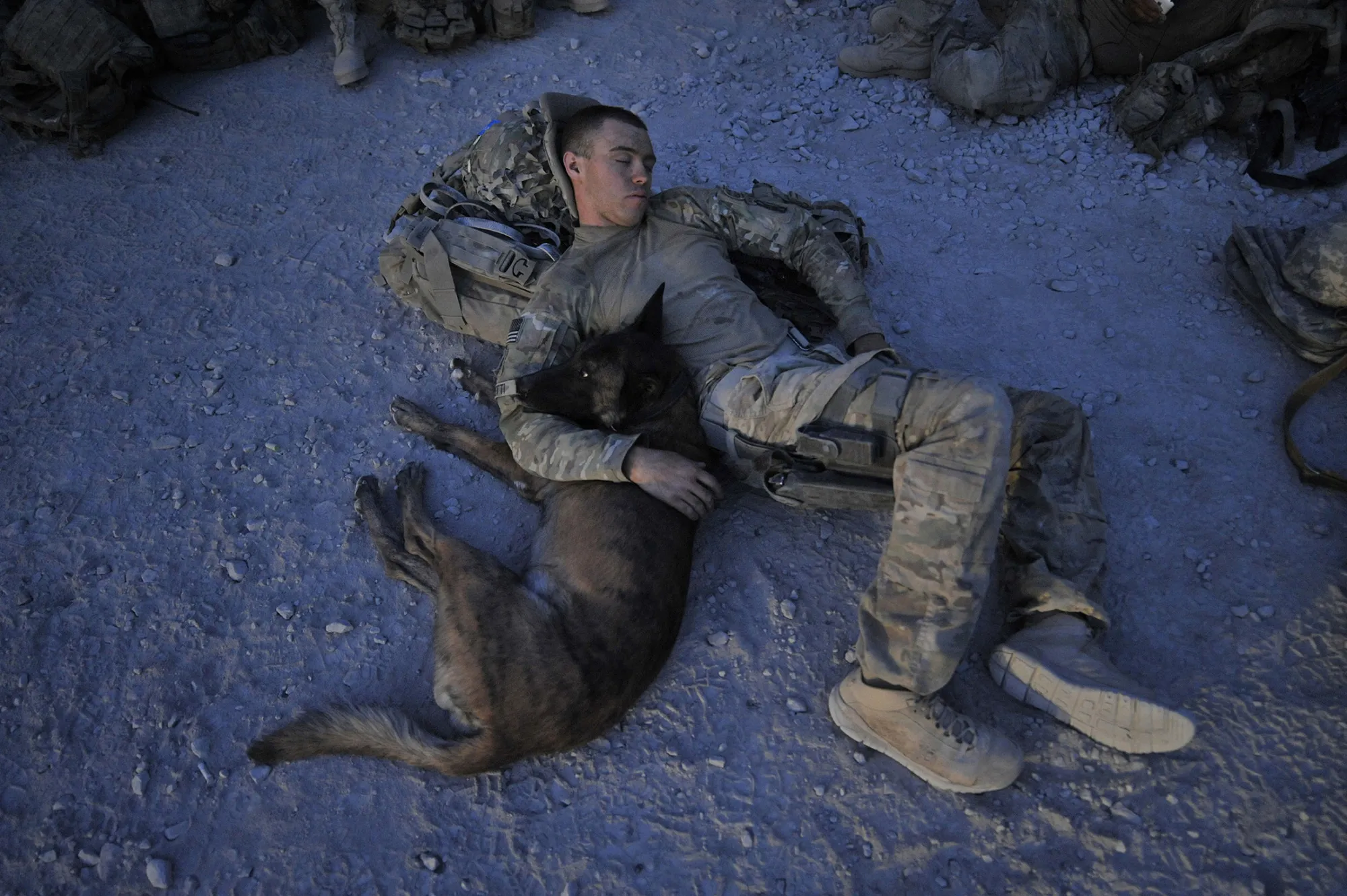 U.S. Army Specialist Justin Coletti, of a K-9 combat tracker team, rests with Dasty, a Belgian Malinois, at an airfield in Afghanistan following an overnight mission.