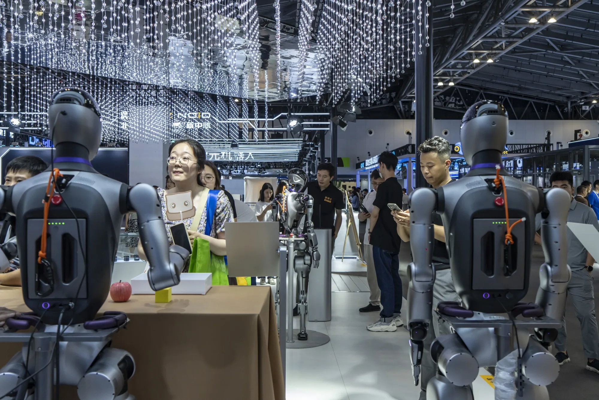 Attendees interact with humanoid robots on display at the World Artificial Intelligence Conference&nbsp;2025 in Shanghai on July 26, 2025.&nbsp;