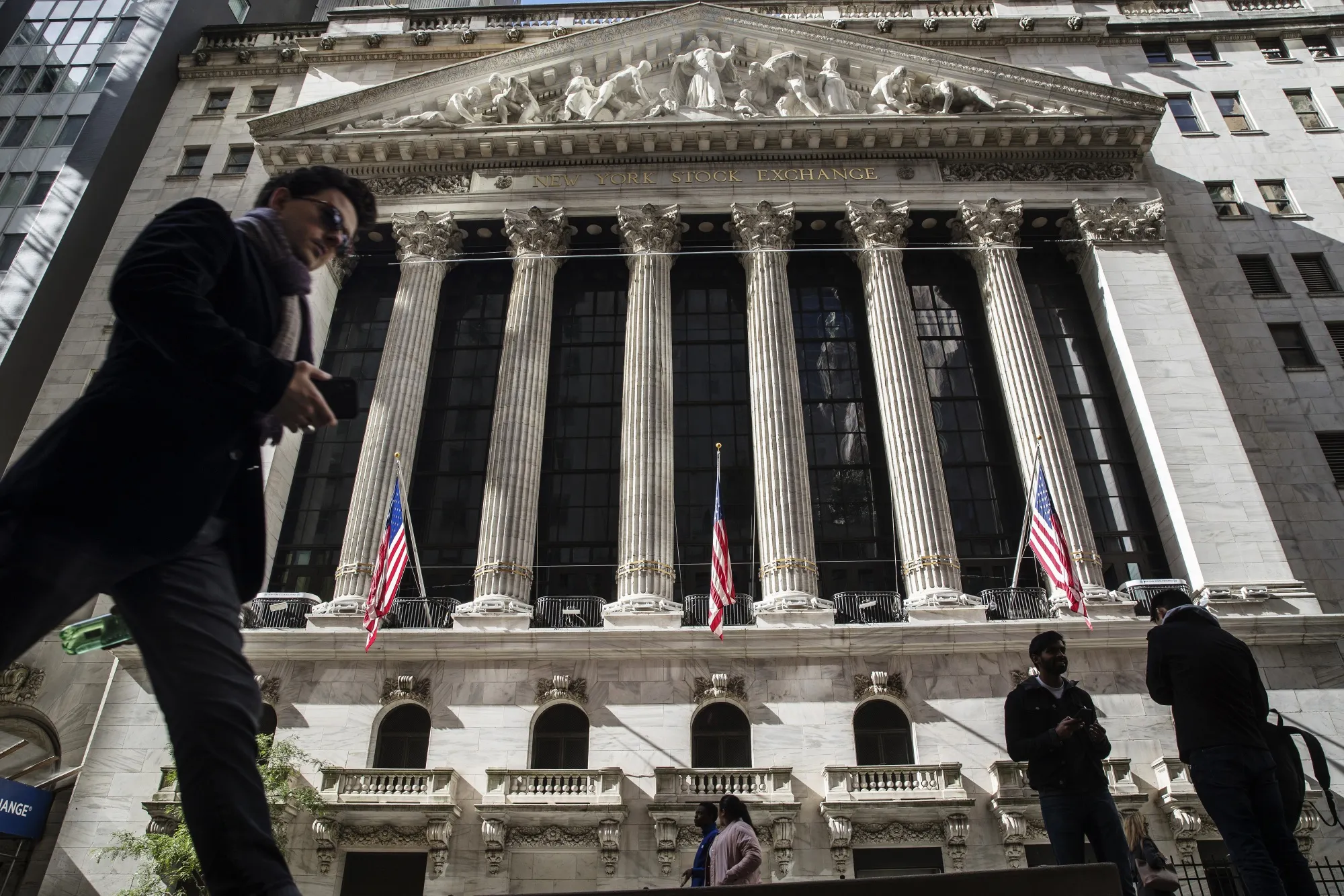 Pedestrians walk on Wall Street in front of the New York Stock Exchange in New York City.