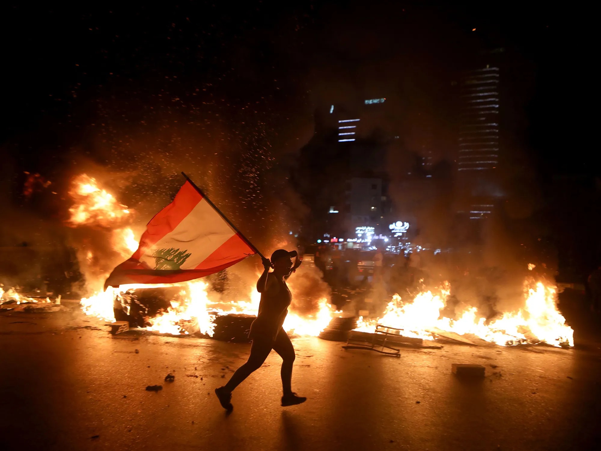 A protester runs near a burning road block in Beirut, Lebanon, on June 11.