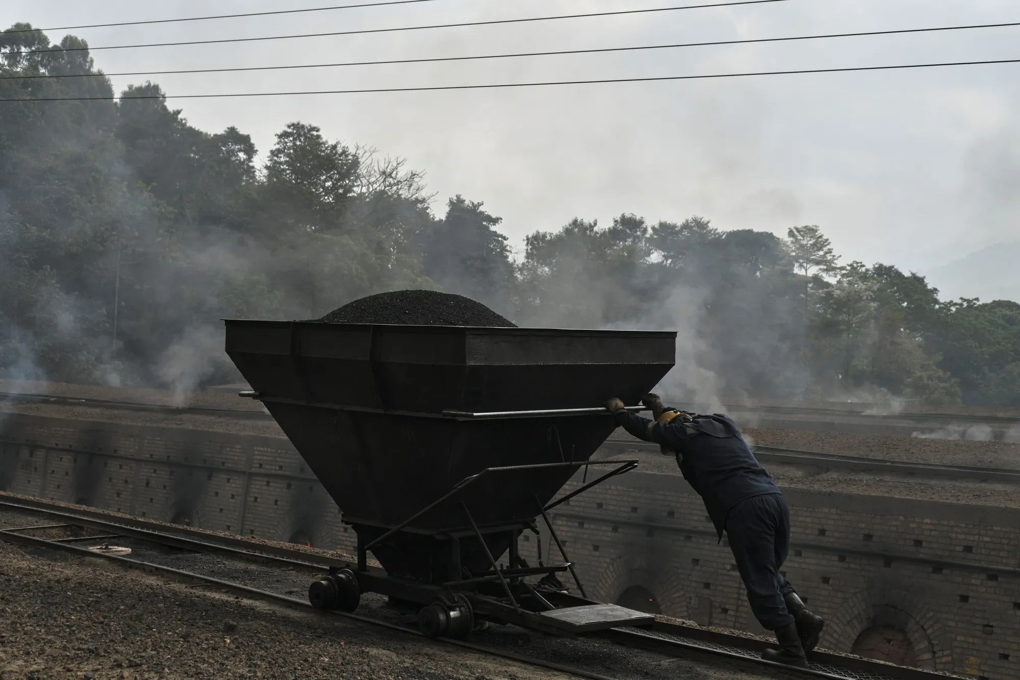 A worker pushes a wagon of coking coal to a kiln at a Carbomax de Colombia facility near Cucuta, Colombia, in 2023.
