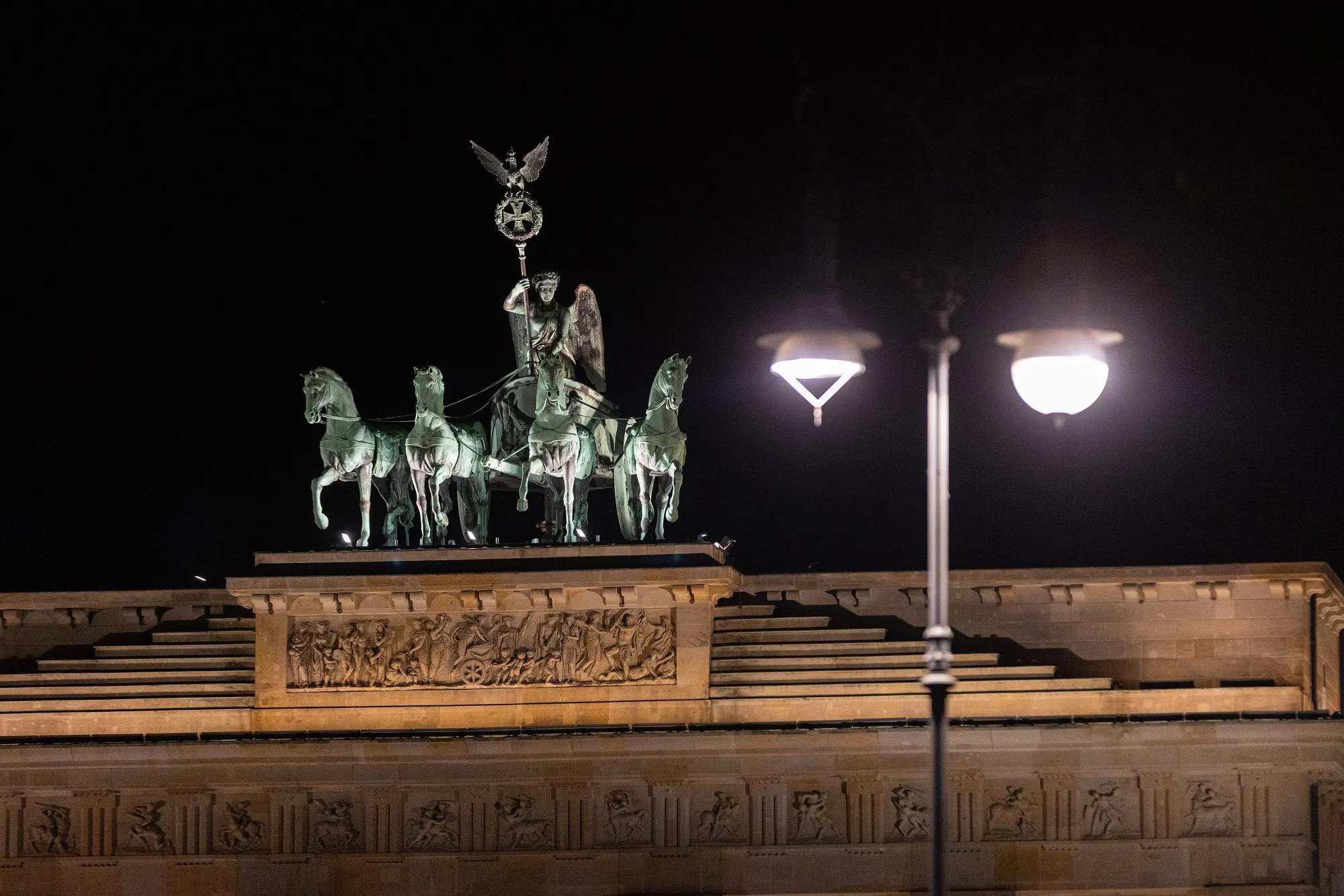 A lit street lamp at the Brandenburg Gate at night in Berlin.