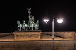 A lit street lamp at the Brandenburg Gate at night in Berlin.
