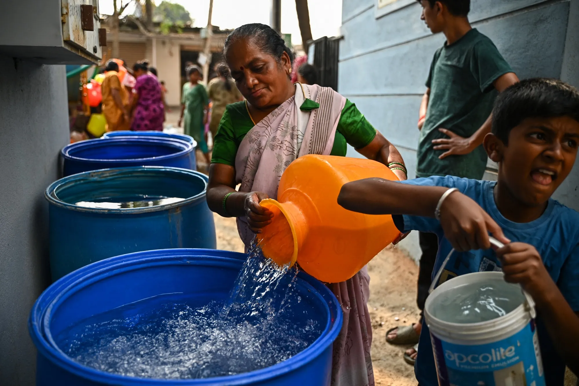 A woman fills a tank at her house with water in Bengaluru on March 15.