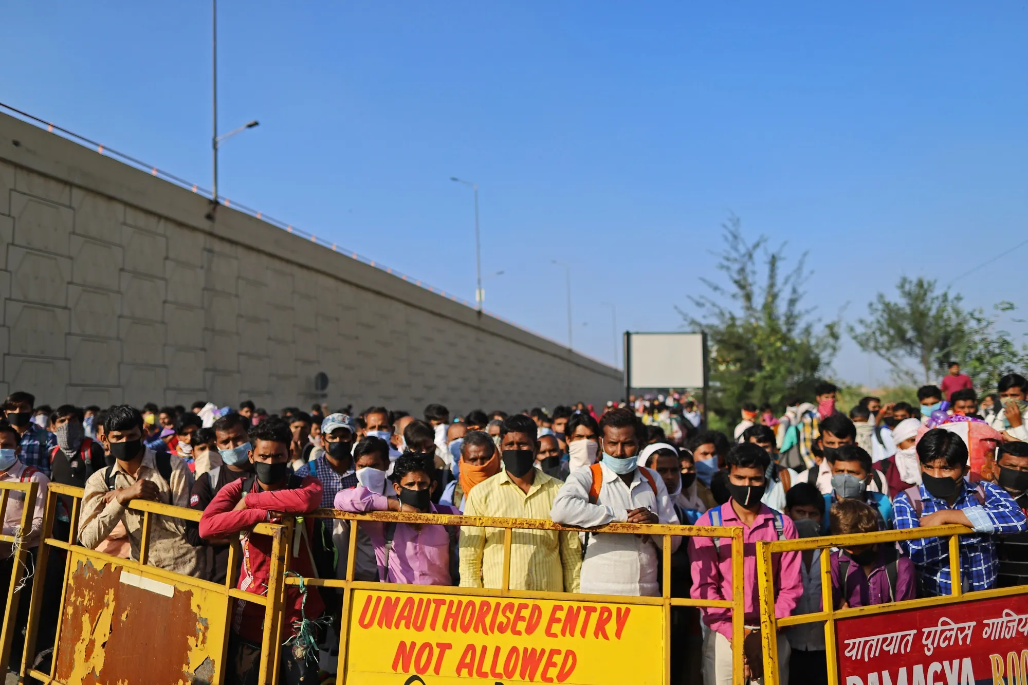Migrant workers and their families wait at a police checkpoint during the coronavirus lockdown  due to the coronavirus in New Delhi, India, on March 28.
