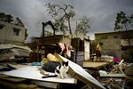 Efrain Diaz Figueroa, right, walks by his sister's home destroyed in the passing of Hurricane Maria, in San Juan, Puerto Rico. The 70-year-old is waiting for a sister to come take him to stay with family in Boston. “I’m going to the U.S. I’ll live better there,” he said.
