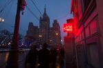 Pedestrians pass a neon sign displaying the latest Russian ruble, euro and dollar exchange rates
