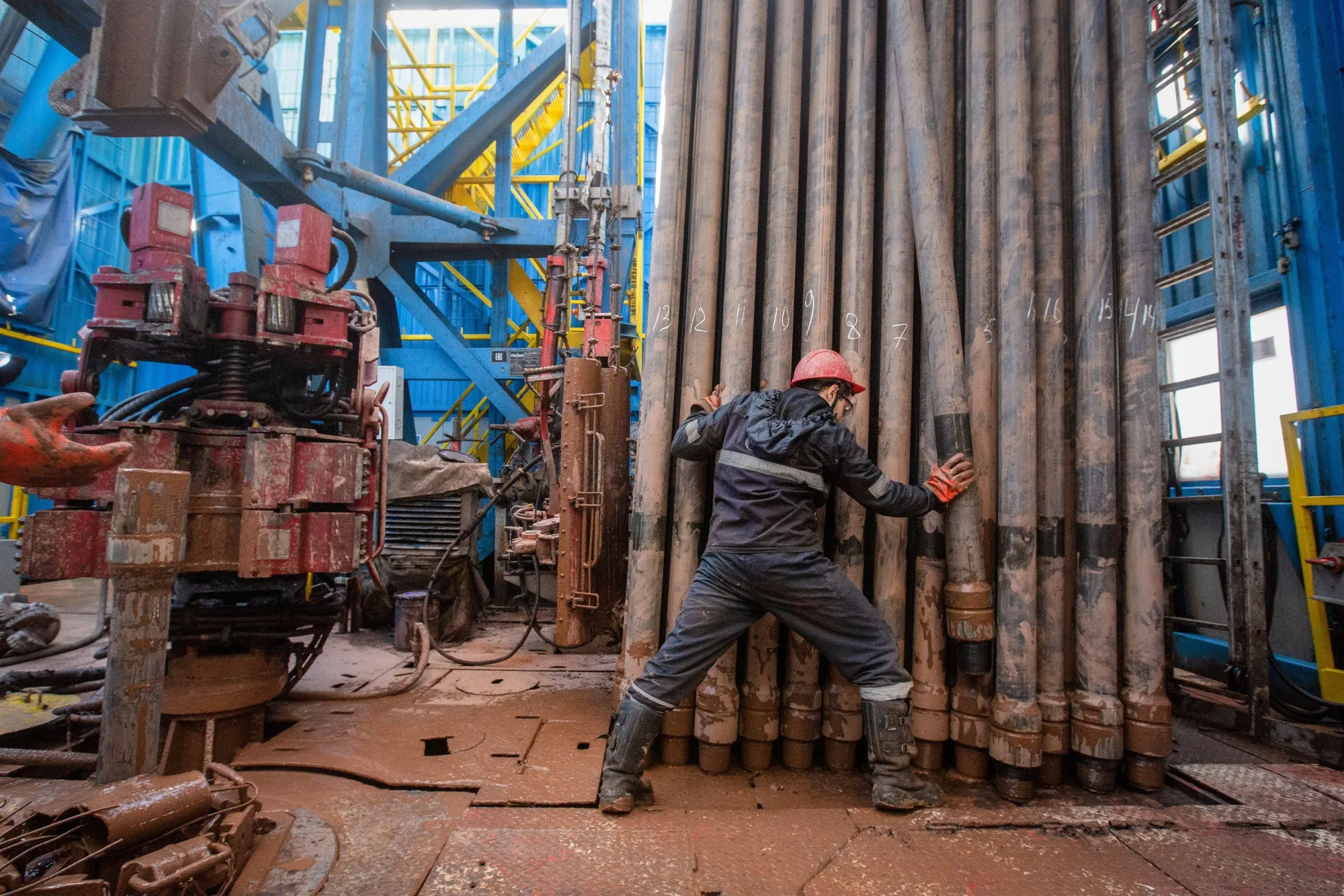A worker moves drilling pipes at a&nbsp;gas drilling rig.