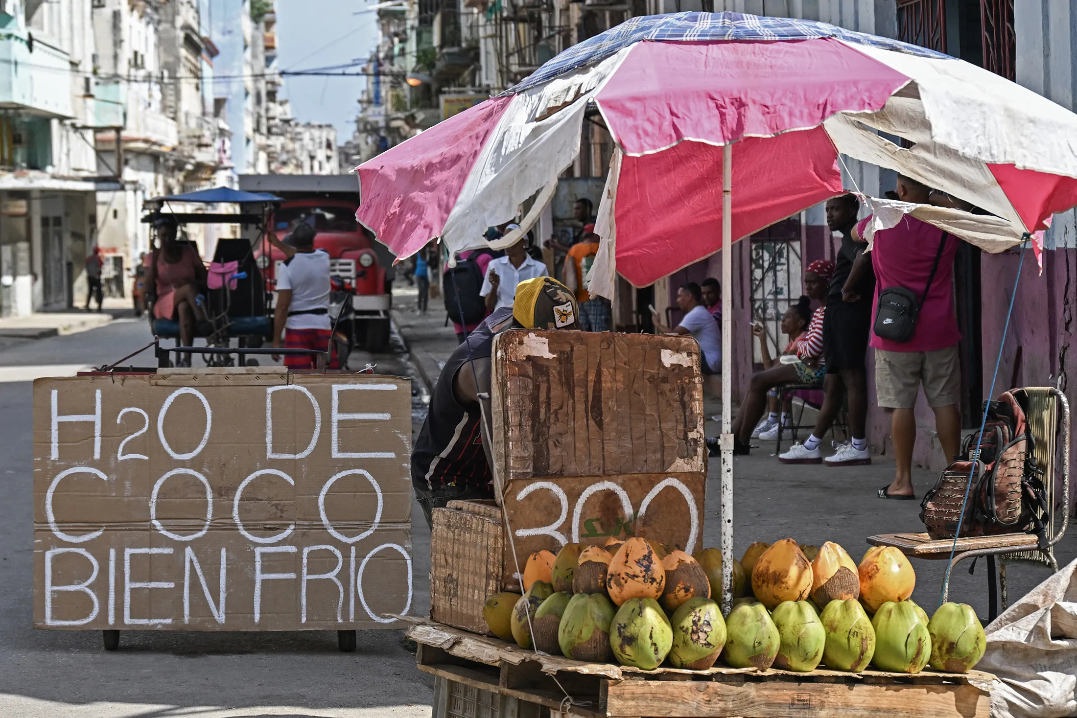 A coconut water vendor as resident sit on the street in Havana on March 16.