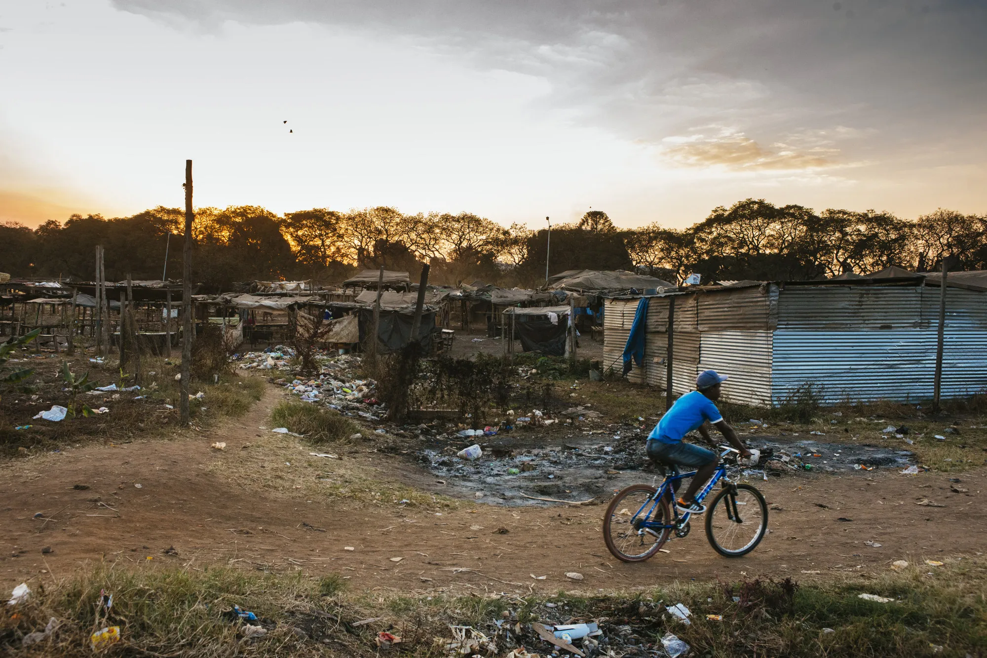 A cyclist rides along a dirt track past shanty dwellings in the Mbare&nbsp;township in Harare, Zimbabwe.&nbsp;