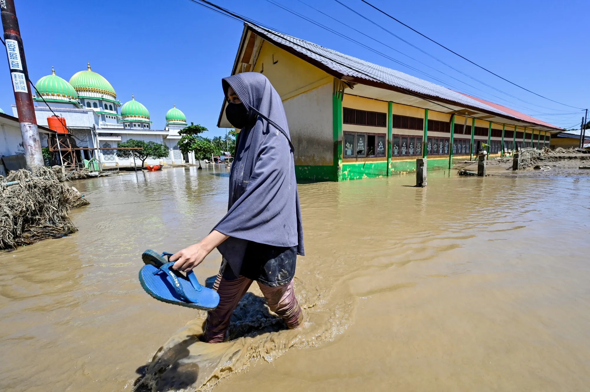 A woman walks past a mosque in a flooded area in Aceh province in Nov. 2025.