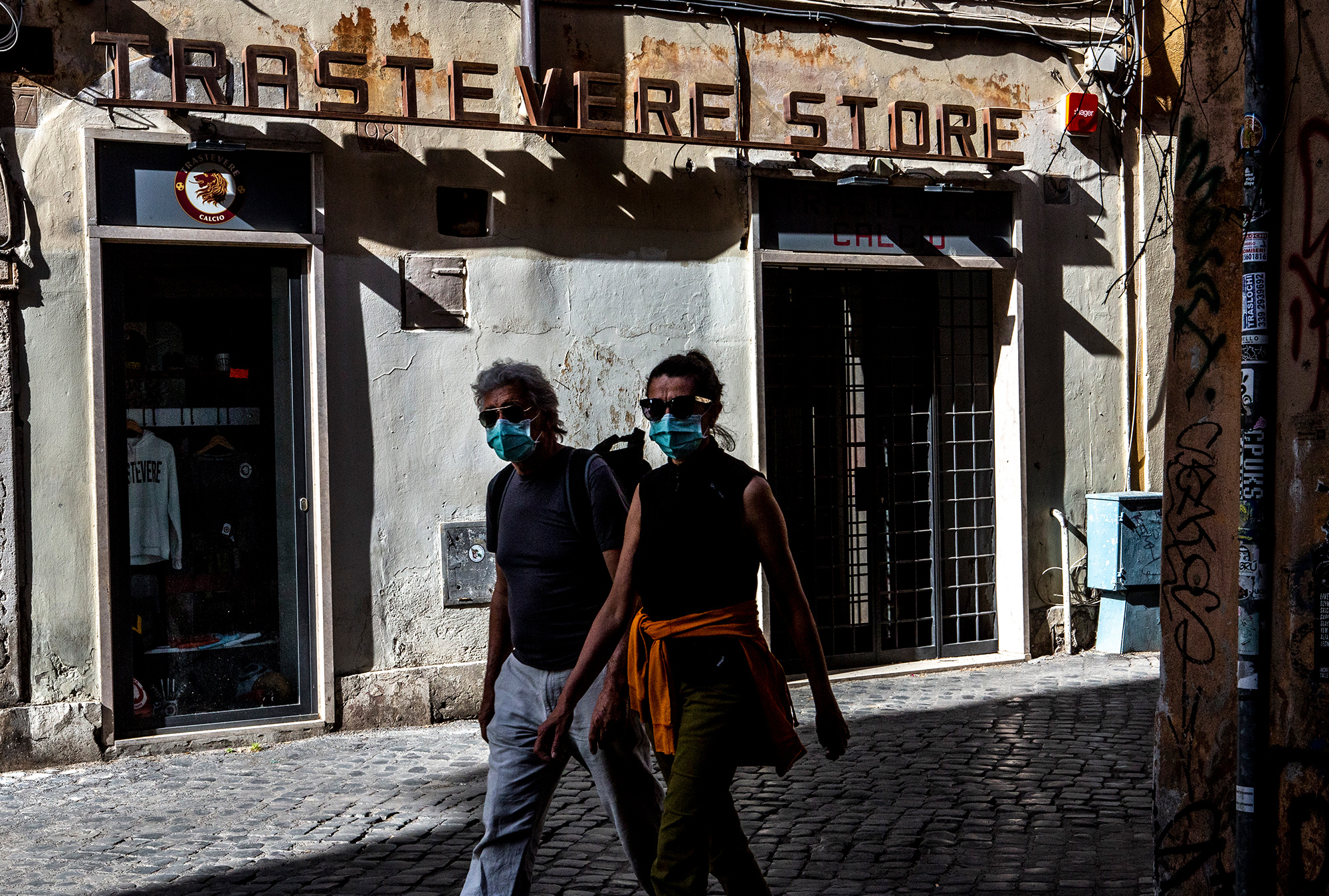 A couple walk past a closed store in the old Trastevere district in Rome, on May 10.