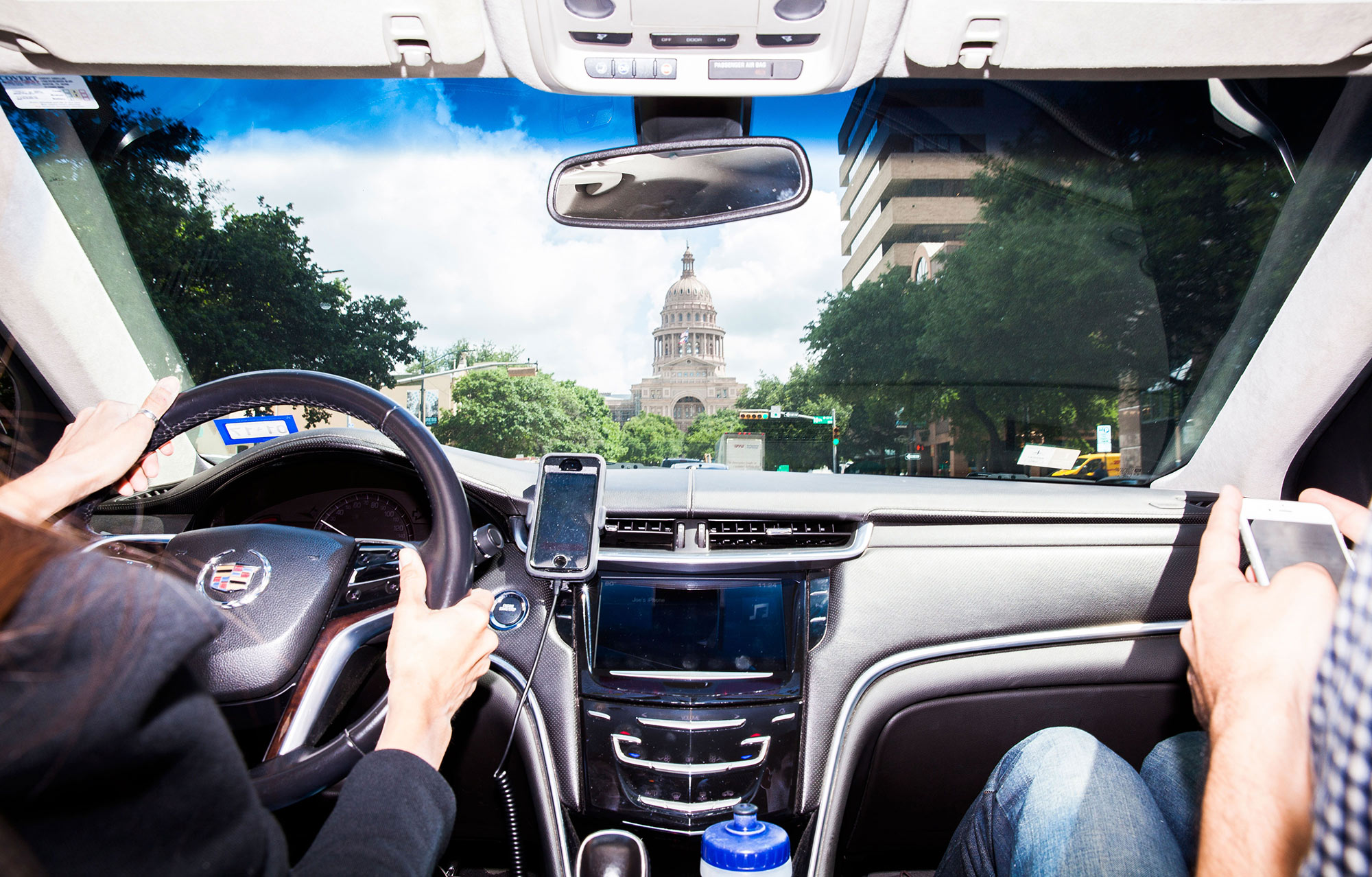 Drivers in a General Motors Co. brand Cadillac vehicle sit facing the Texas State Capitol building in Austin, Texas, U.S., on Friday, June 3, 2016. Steve Adler, Austin's mayor, thinks he can put his stamp on the city by burnishing its reputation as an exciting playground for experiments in urban transportation. One of his political priorities is to seek millions in federal funding to promote a so-called smart city plan based on autonomous buses, sensors that know which parking spaces are available and, yes, a culture of ridesharing.
