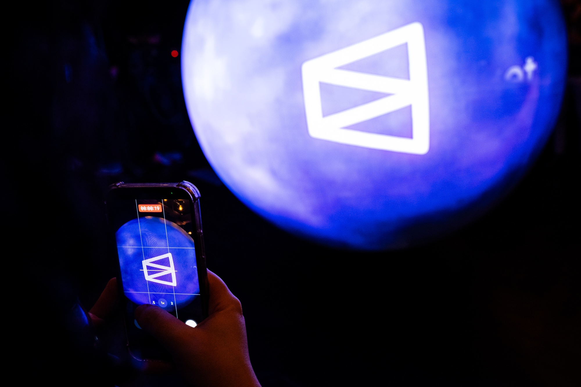 An attendee takes photos of the Polymarket logo displayed on an electronic sphere during the opening of The Situation Room by Polymarket pop-up bar in Washington, DC, US, on Friday, March 20, 2026. Polymarket took over a bar near the White House, for a promotional event showcasing the prediction market’s vision of betting on current events as a new form of entertainment. Photographer: Graeme Sloan/Bloomberg