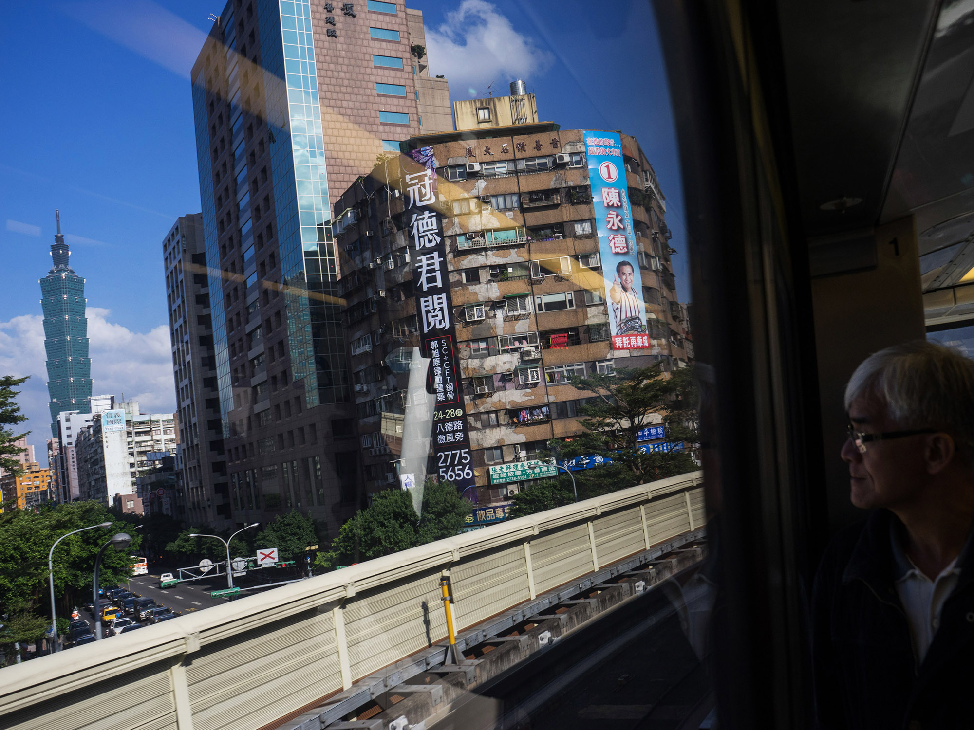 A passenger looks out at the Taipei 101 building, left, and other commercial and residential buildings from a Mass Rapid Transit (MRT) train, operated by Taipei Rapid Transit Corp., as it travels along an elevated track in Taipei, Taiwan.