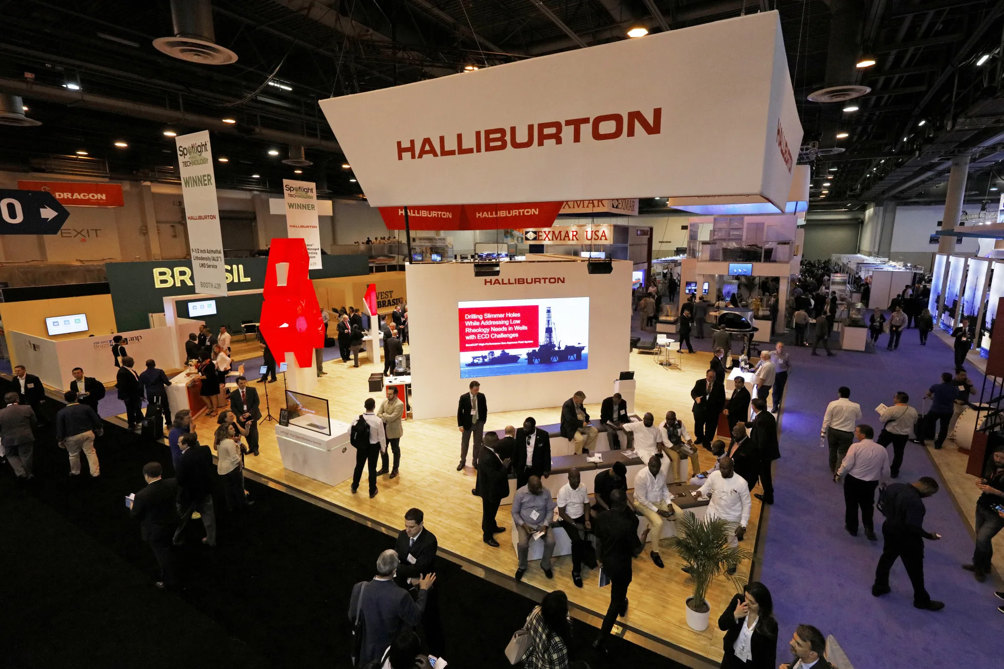 Attendees pass in front of the Halliburton Co. booth during the Offshore Technology Conference&nbsp;in Houston, Texas.