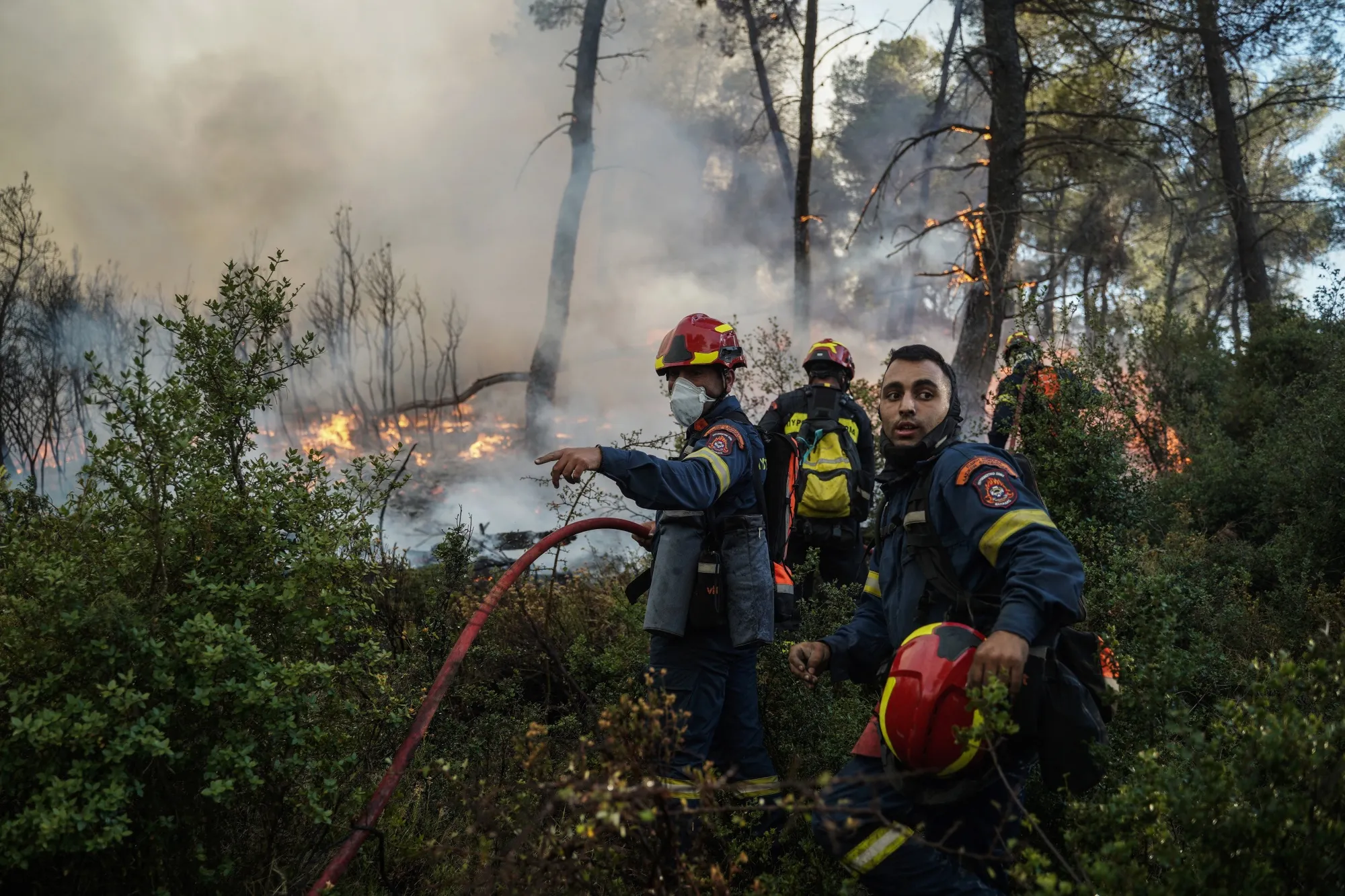 Firefighters work to extinguish a wildfire near the town of Stamata, northeast of Athens, Greece, on June 30.