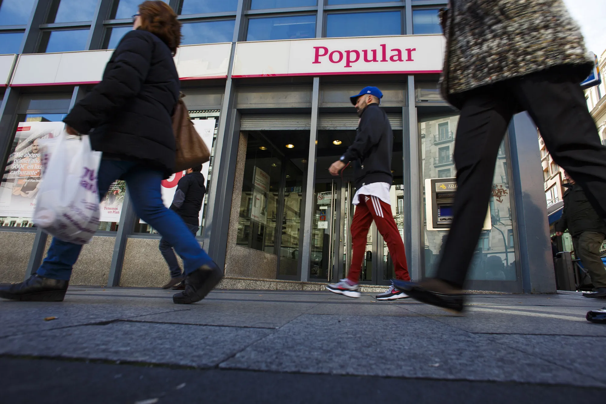Pedestrians pass a Banco Popular Espanol SA bank branch in Madrid.
