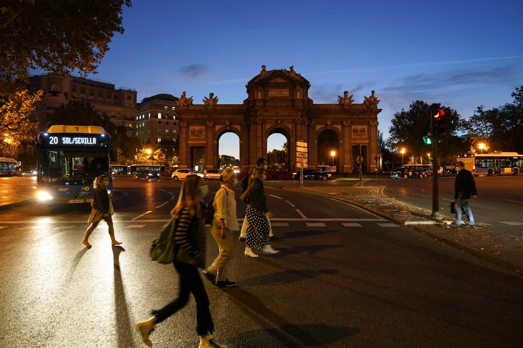 Early morning commuters cross the street in front of the Puerta de Alcala monument in Madrid, on Oct. 8.