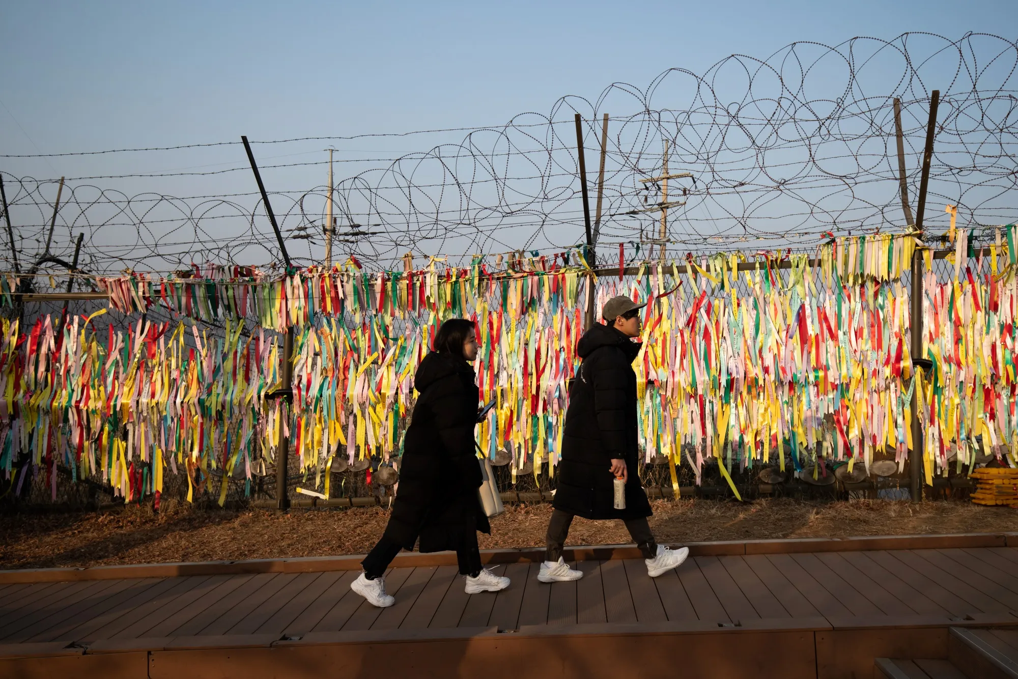 Visitors walk past ribbons hanging from a barbed-wire fence at the Imjingak pavilion near the demilitarized zone in Paju, South Korea.