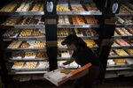 A employee places donuts in a box for a customer at a Dunkin' Donuts Inc. location in Los Angeles.