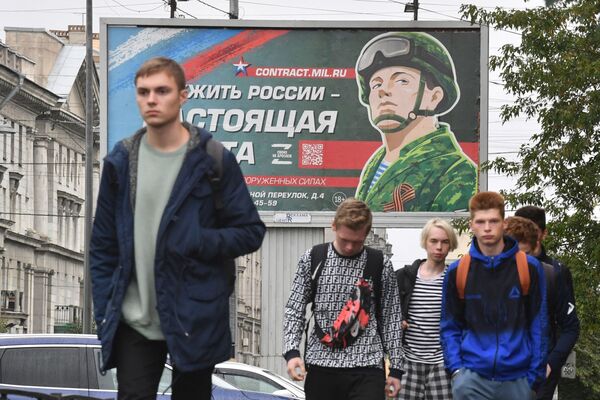 Young men walk past a billboard promoting contract army services in St. Petersburg, Russia.