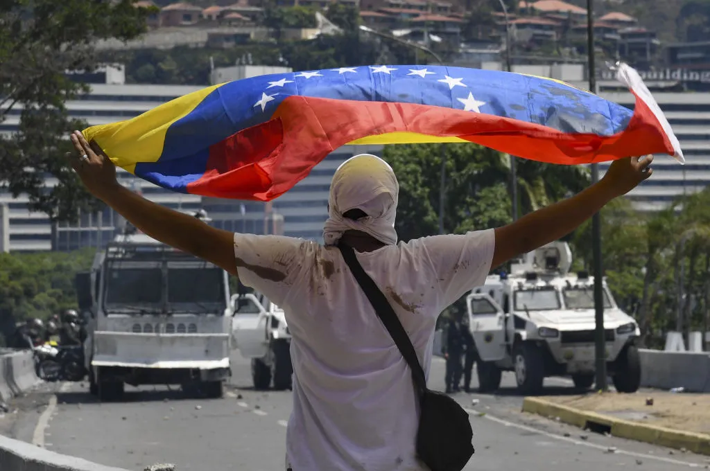 A supporter of Venezuelan opposition leader and self-proclaimed acting president Juan Guaido displays a national flag during clash with forces loyal to President Nicolas Maduro.