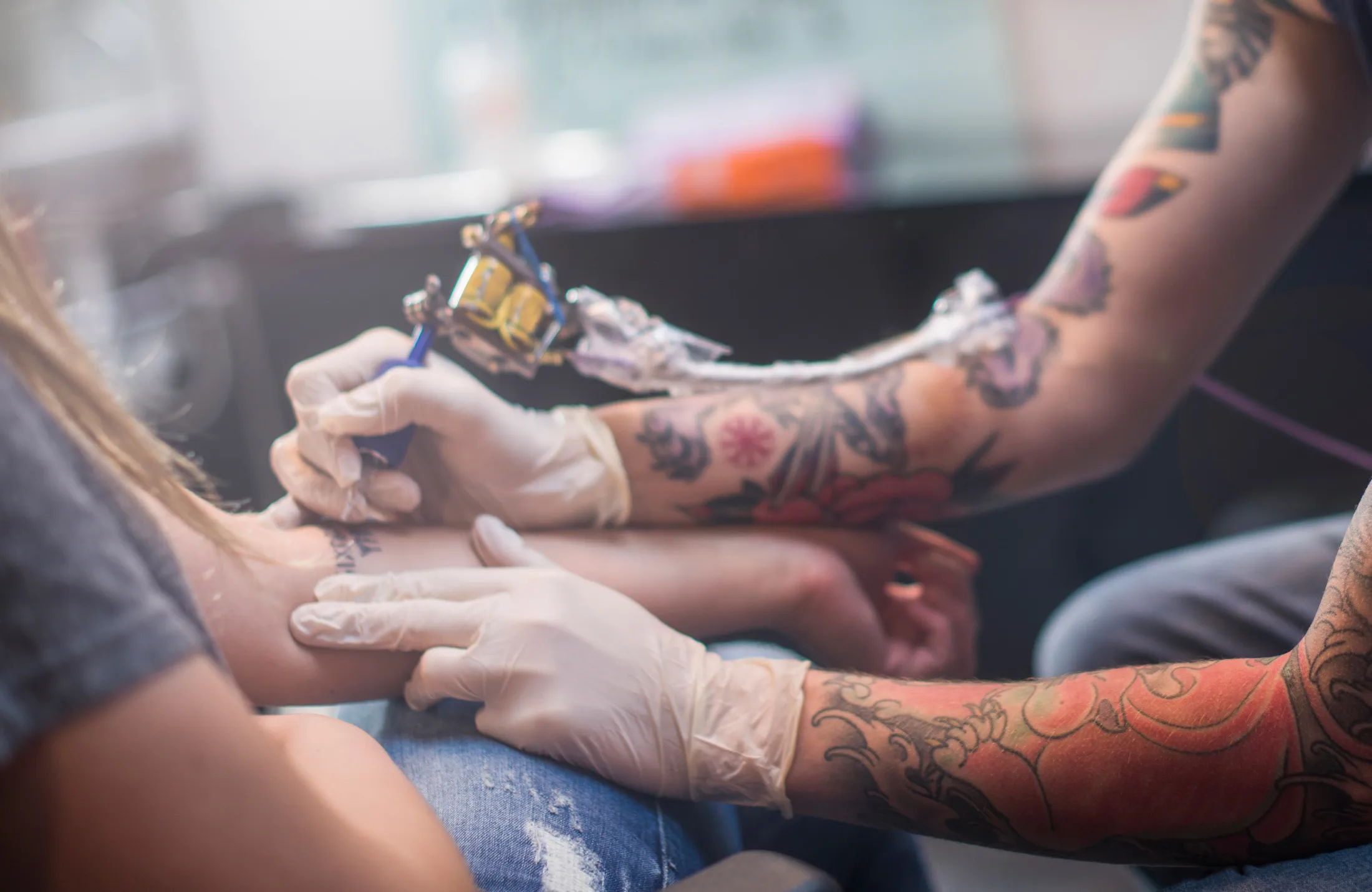 A tattoo artist working on a customer's arm.