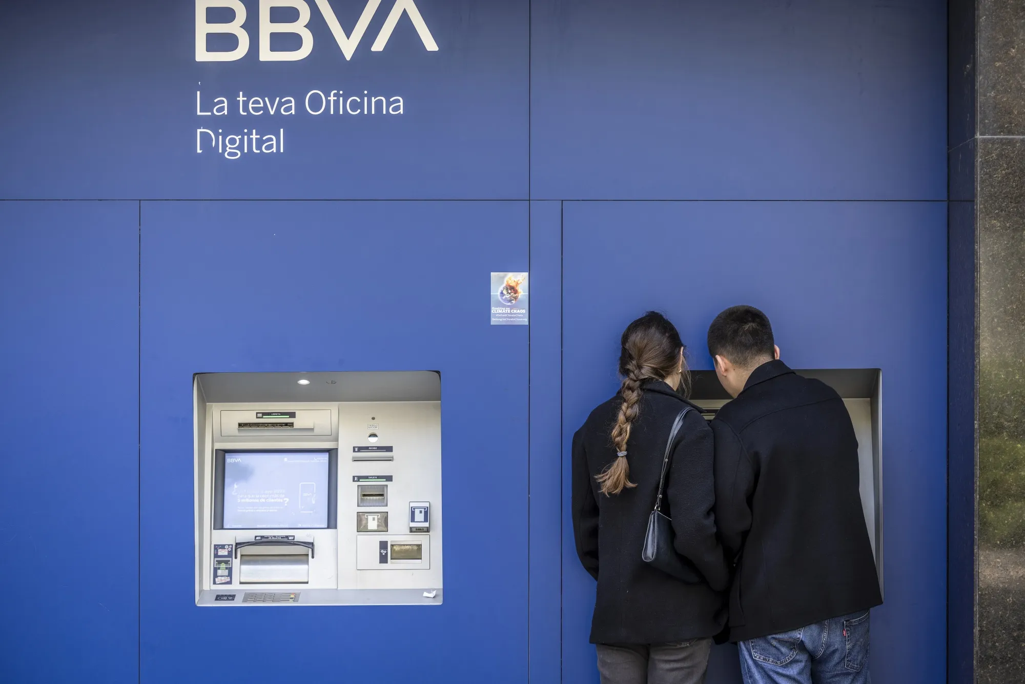 Customers use an&nbsp;ATM&nbsp;outside a BBVA&nbsp;bank in Barcelona, Spain.
