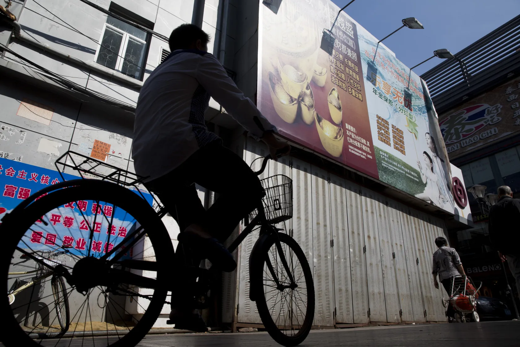 A man rides a bicycle in the Gongbei district of Zhuhai, Guangdong province, China, on Sunday, Nov. 16, 2014. China’s economy, burdened by overcapacity and weak domestic demand, is headed for the slowest full-year growth in more than two decades.