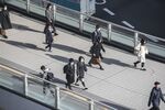 Morning commuters wearing protective masks walk on a footbridge in Tokyo, Japan.