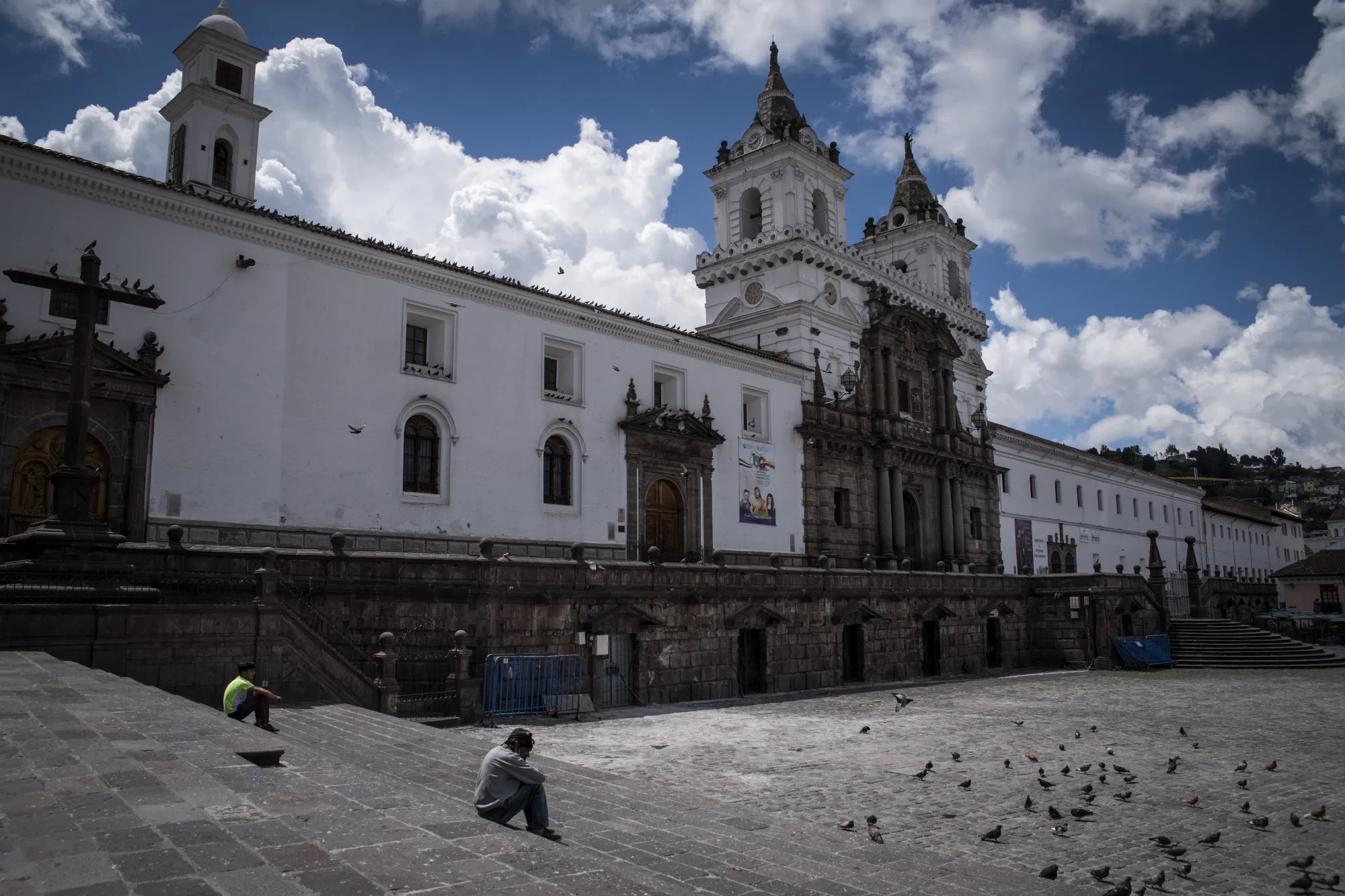 Pedestrians sit outside of the closed San Francisco Church on Palm Sunday in Quito on April 5.