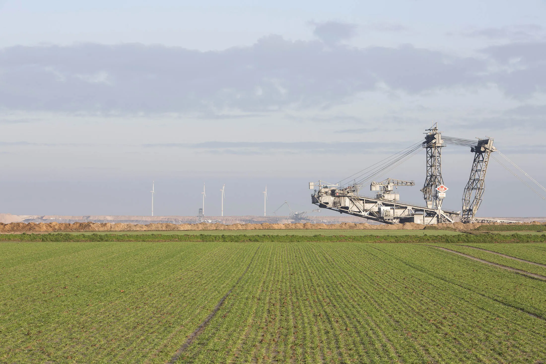 A giant excavator operates beyond agricultural land at the Garzweiler open cast lignite mine, operated by RWE AG, in Garzweiler, Germany, on Tuesday, Dec. 15, 2015. Global governments and companies are counting the costs and benefits from the United Nations COP21 climate agreement, which calls for wholesale transformations of energy, transportation, and dozens of other lines of business.
