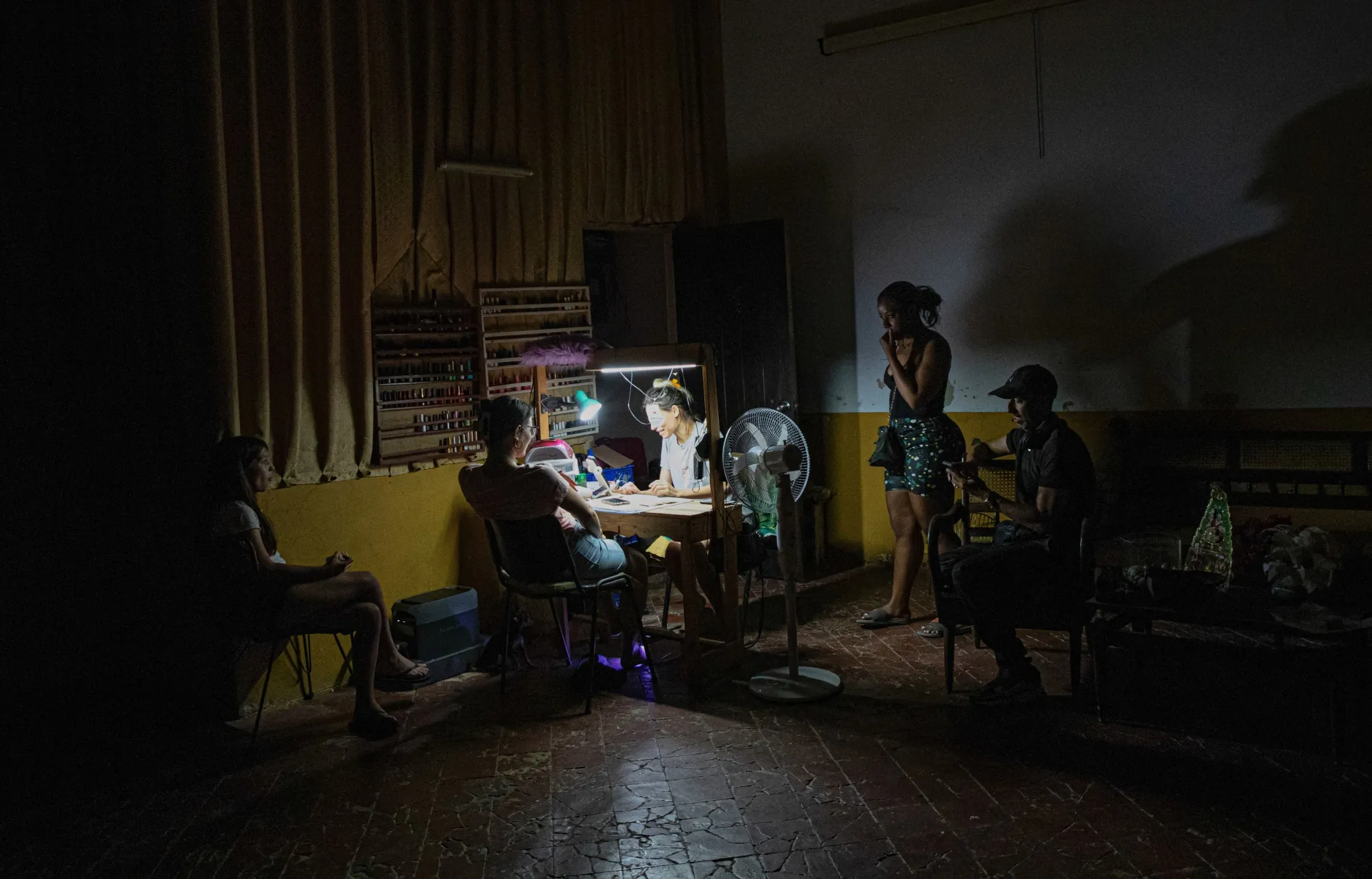 A worker paints customers' nails by the light of rechargeable lamps during a blackout in Matanzas, Cuba, on April 6.