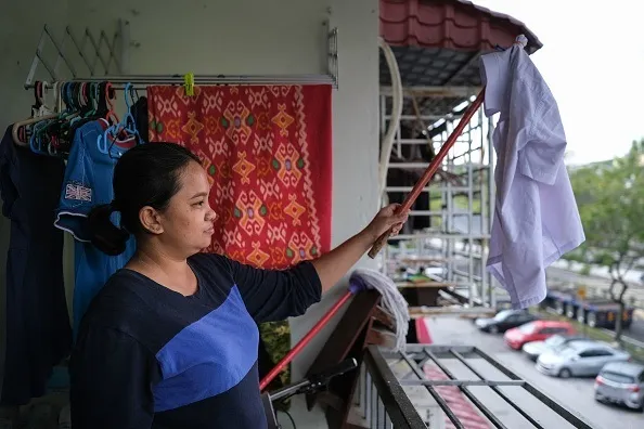 Tilda Kalaivani waves a shirt as a white flag from her apartment balcony in Kuala Lumpur.