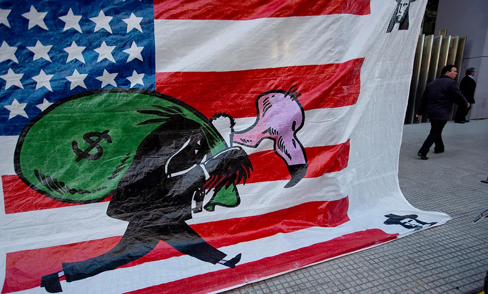 A banner shows a vulture, symbolizing a U.S. hedge fund, carrying a bag of money in front of the U.S. flag outside Congress in Buenos Aires, Argentina.
