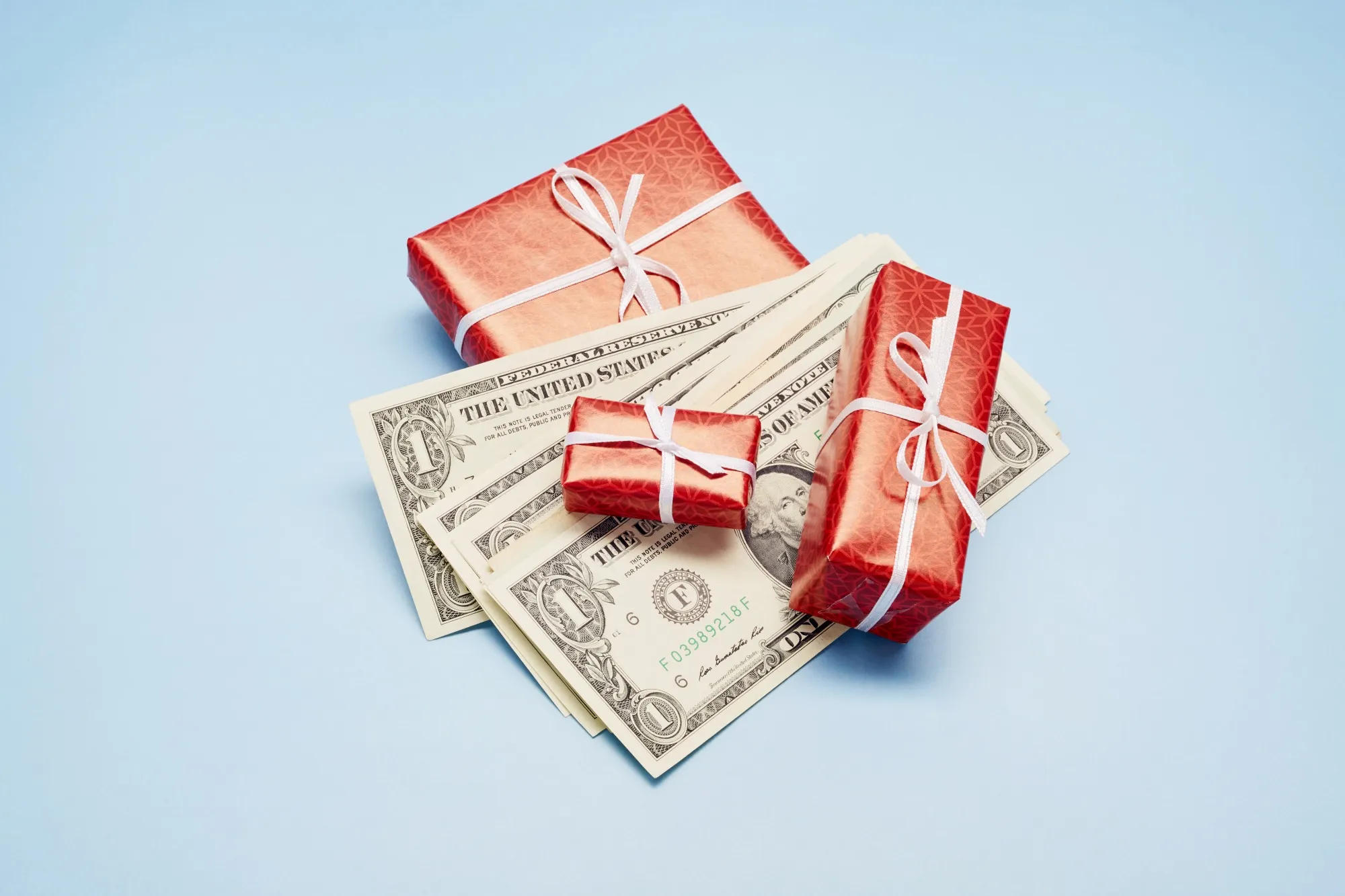 High angle view of wrapped Christmas presents and American Dollar banknotes on blue background, Christmas bonus