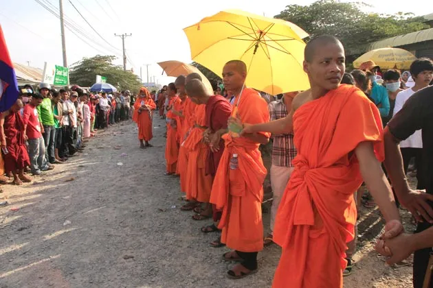 Cambodian Buddhist monks stand together as they participate in a garment workers strike in front of a factory on the outskirts of Phnom Penh, Cambodia, on Jan. 2