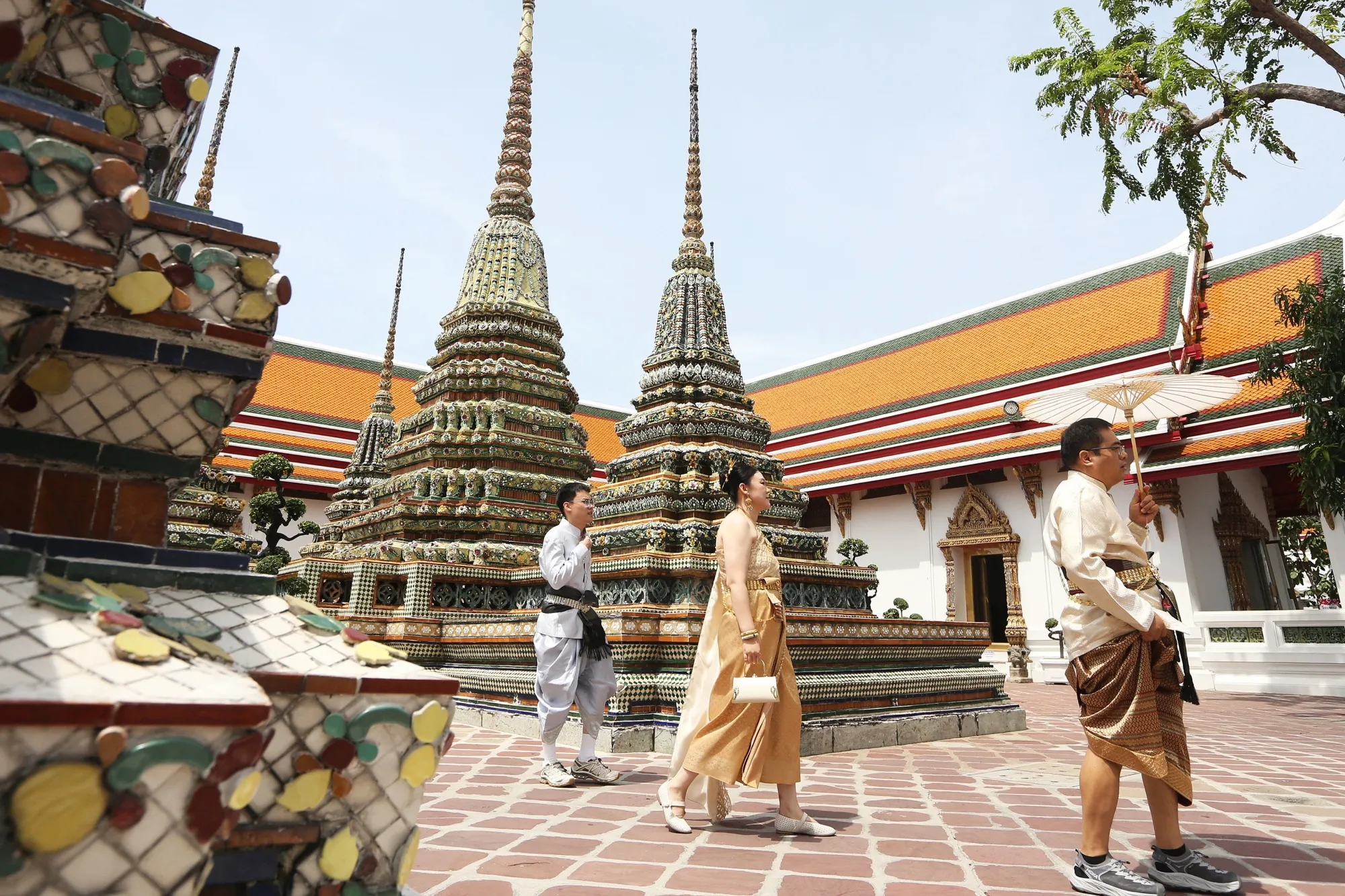 Tourists in traditional Thai costumes visit the Wat Pho temple in Bangkok.