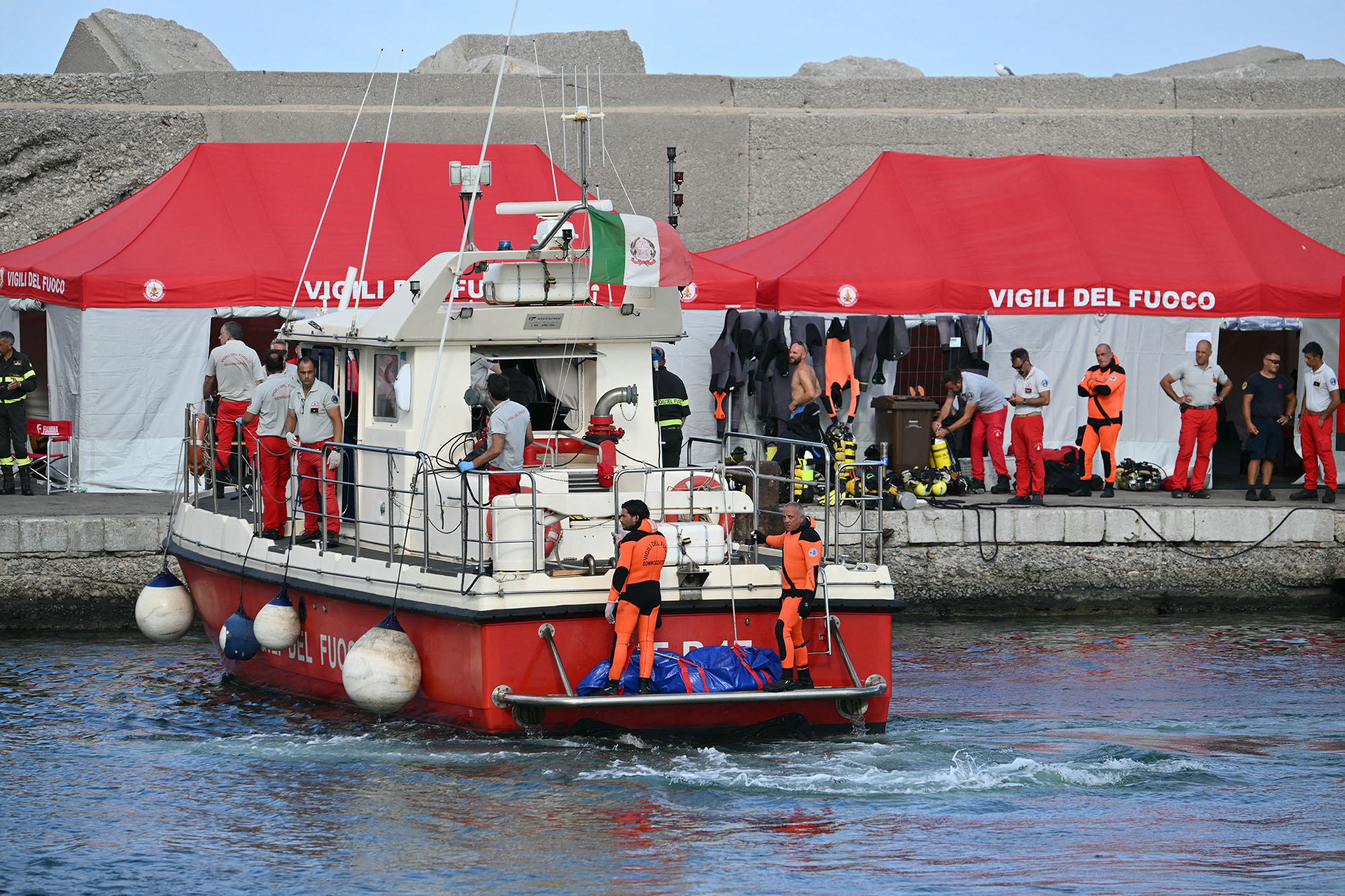 Divers of the Italian Corps. of Firefighters arrive&nbsp; with a third body at the back of the boat&nbsp;in Porticello harbor near Palermo, Italy,&nbsp;on Aug. 21.