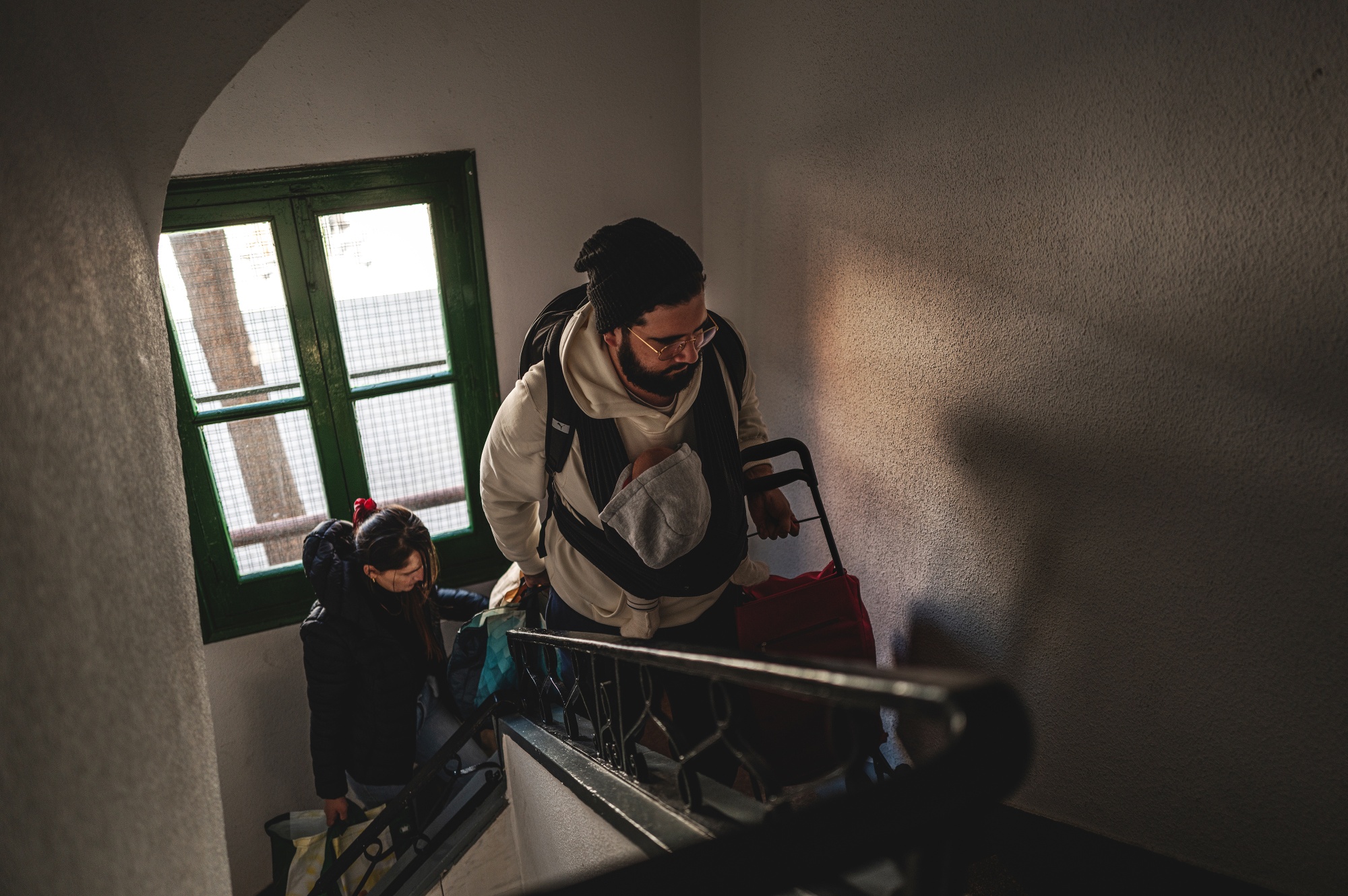 Jeniffer, Alfredo and their baby, walk up the stairs of their building as they return home in Madrid, Spain, on Friday, March 13, 2026.