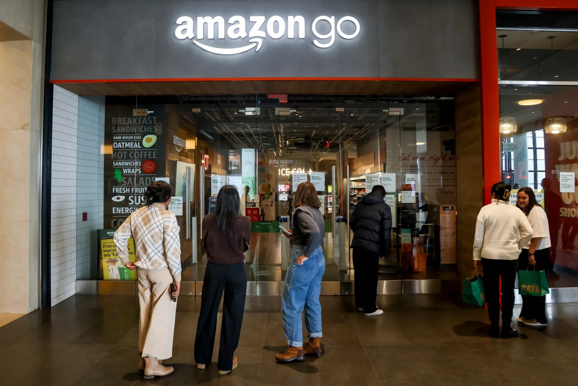 People look at signs stating the closing date of an Amazon Go store in New York on Jan. 27.