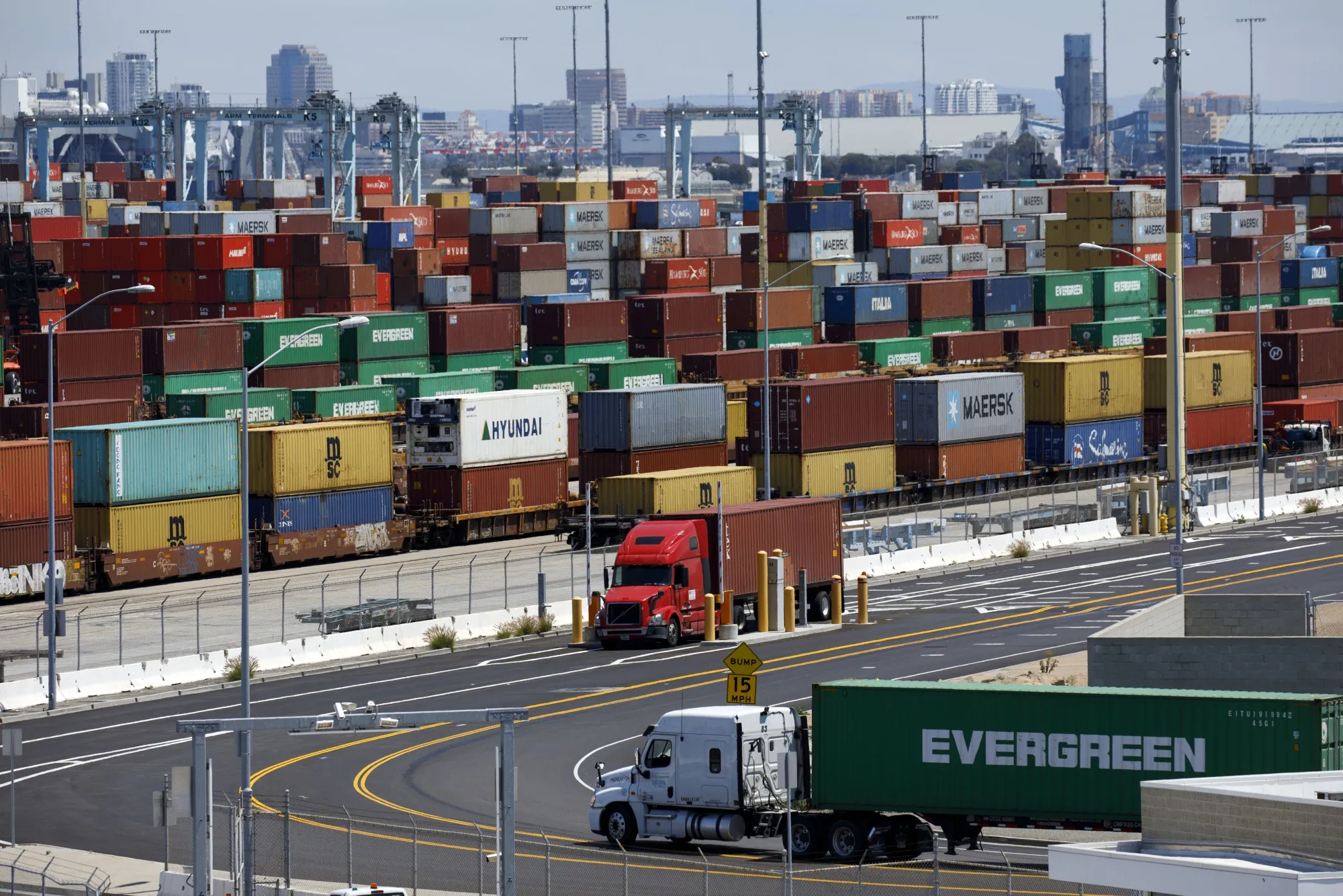Semi-trucks drive past shipping containers at the Port of Los Angeles on May 7.